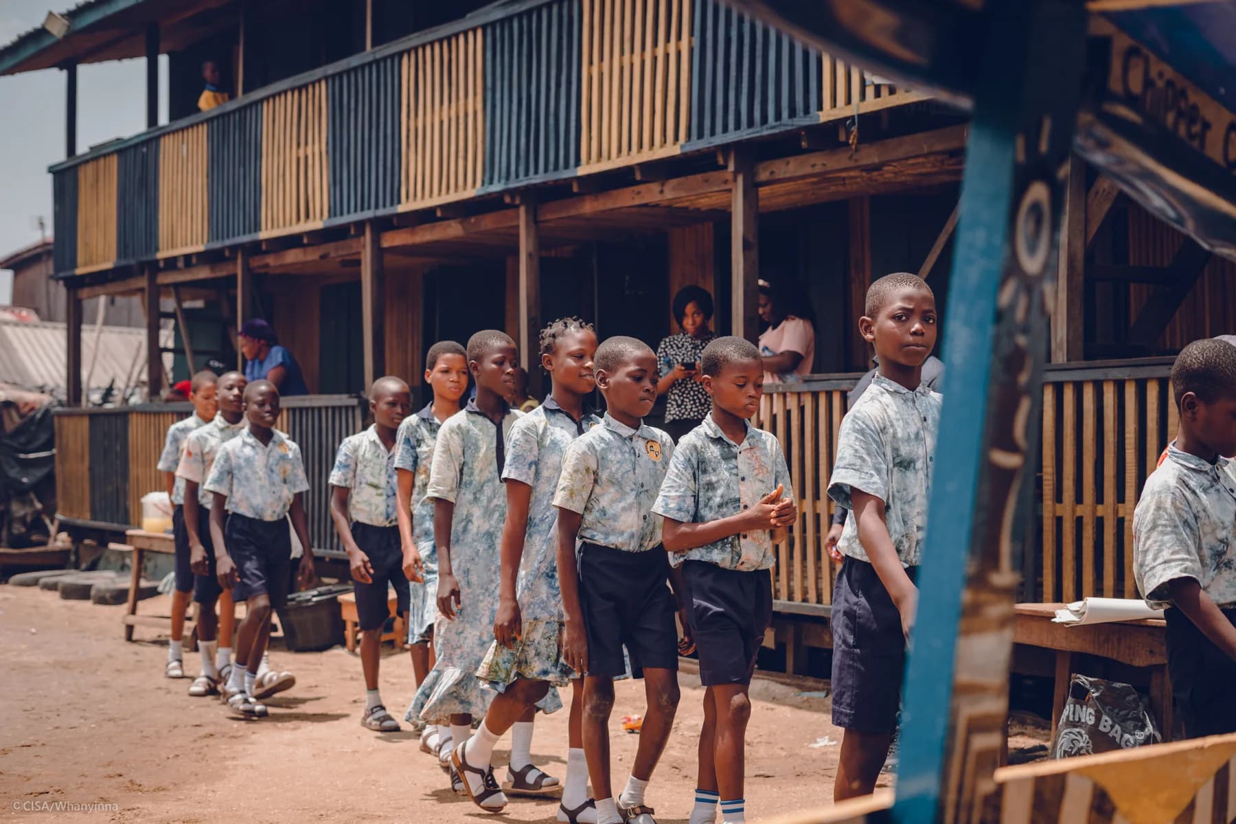 Children walking along a wooden boardwalk over the Makoko lagoon